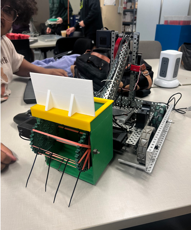 The GOAL In my Interdisciplinary Design and Manufacturing class, we got the opportunity to design a robot to score various foam balls in a competitive arena. My group and I decided on a design that would be heavily focused on speed, ease of building, and something easy to drive for everyone. I modeled and printed the end of the arm tool to grab the game pieces with the zip ties and rubber bands with a vertical storage system, then reversed the motors when in position to score.